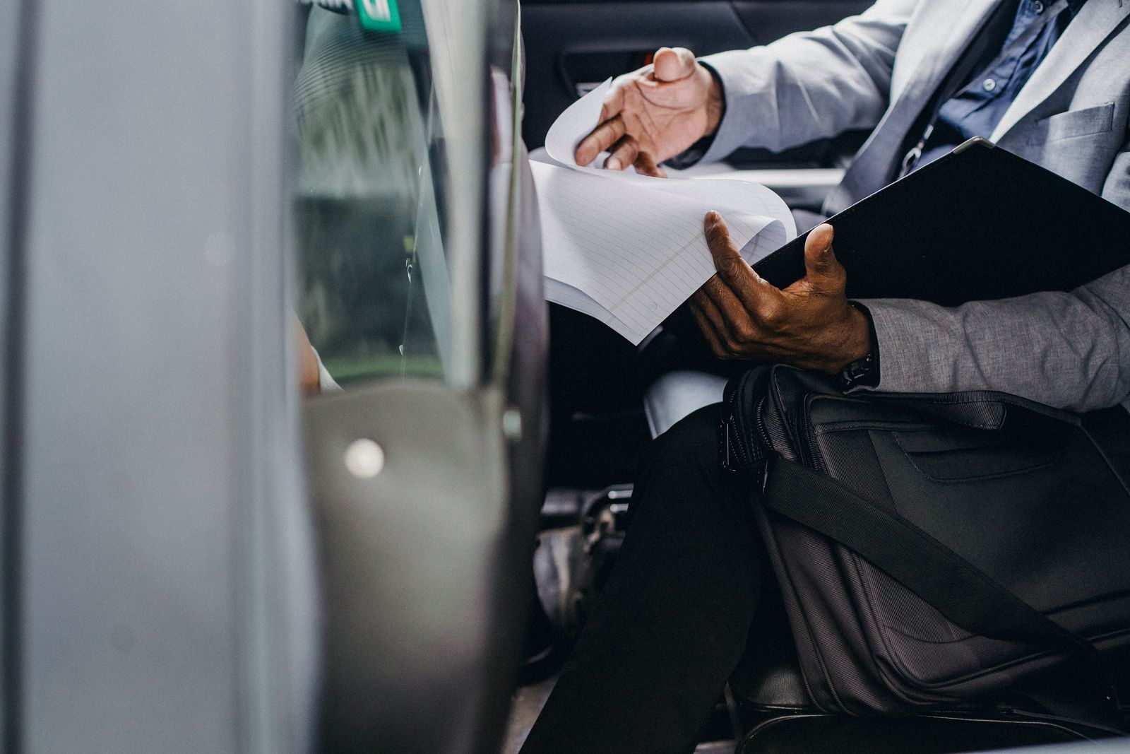 Ejecutivo revisando documentos en el asiento trasero de un coche