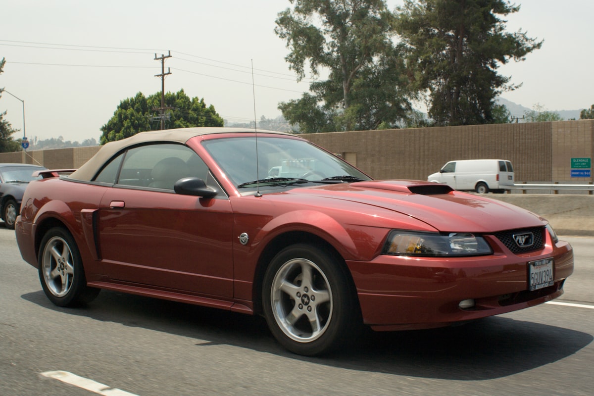 Red convertible top-down parked by palm trees on a European coast