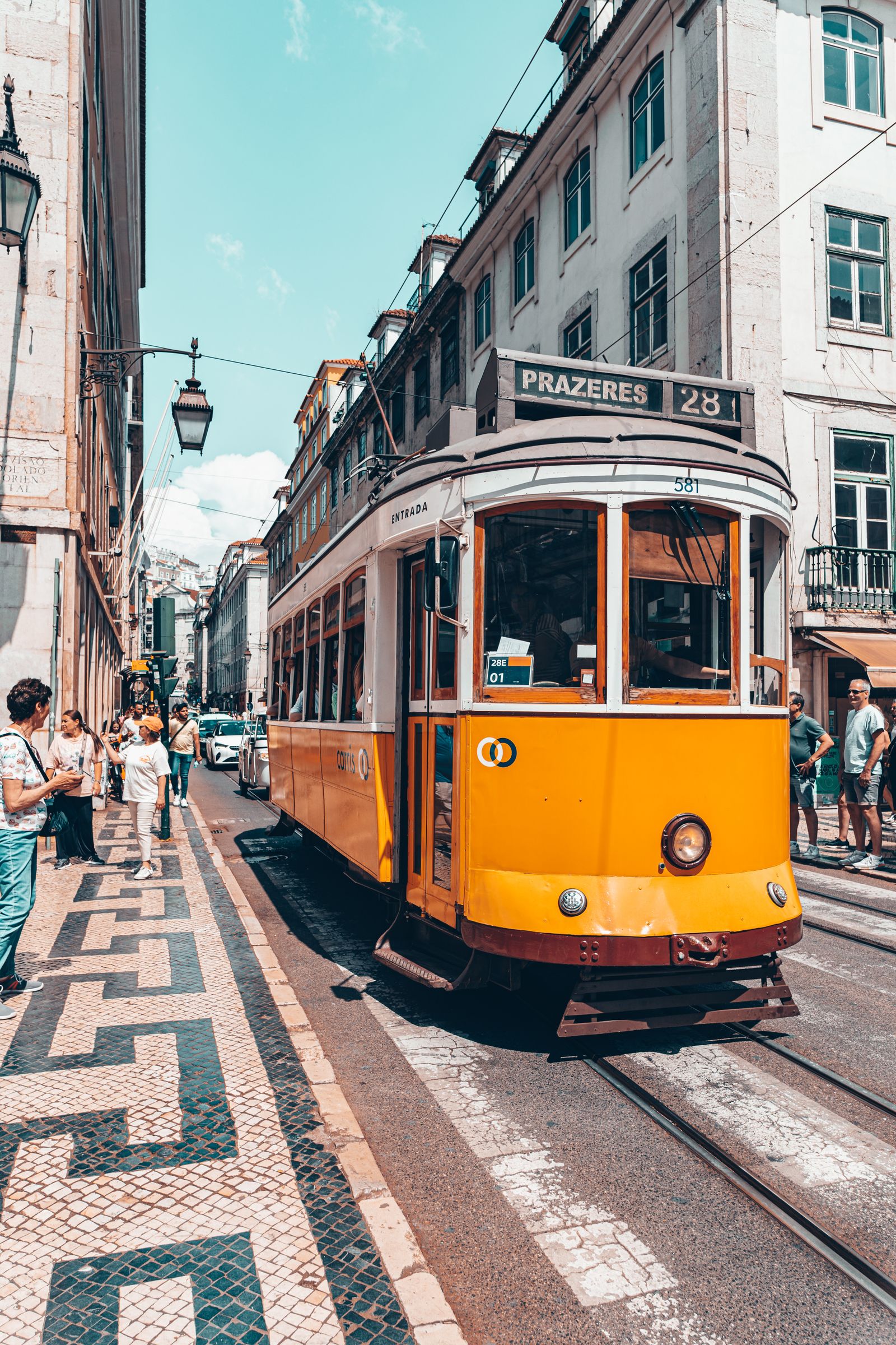 Tranvía 28 amarillo por una calle empedrada de Lisboa