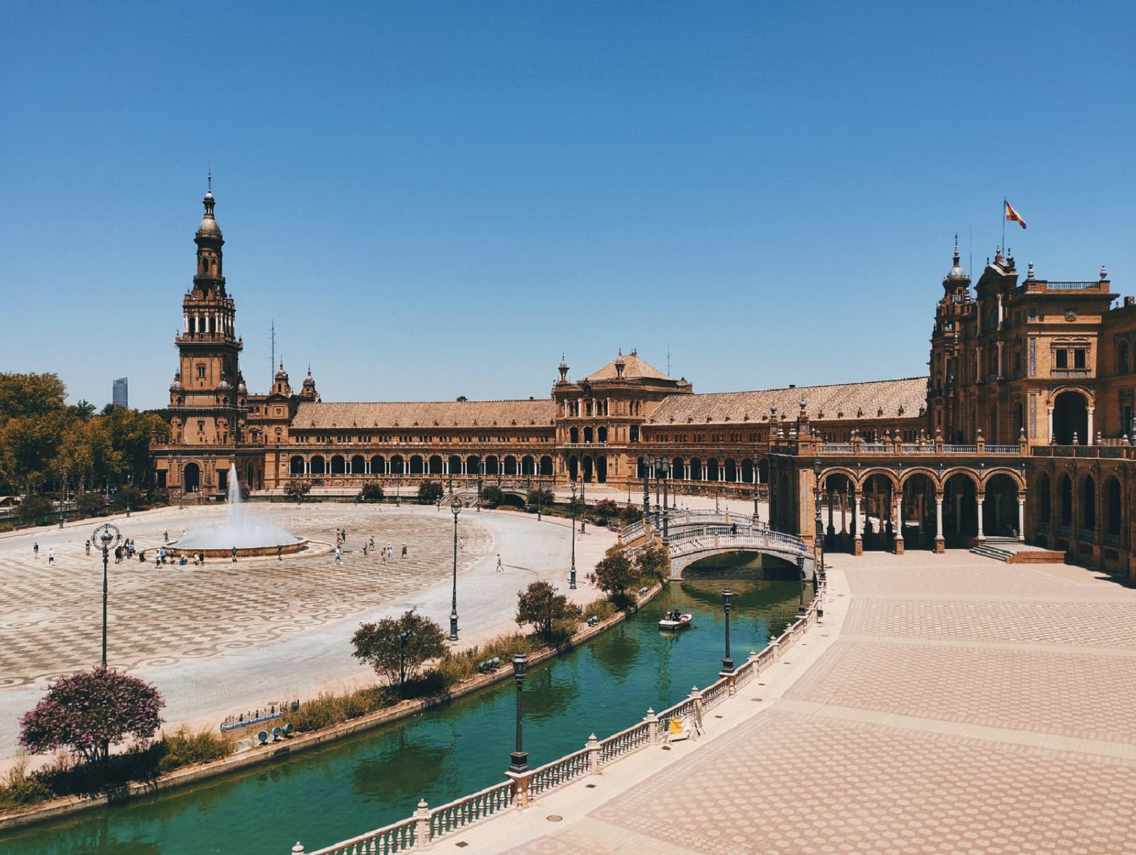 Vista de la Plaza de España de Sevilla con su torre, el canal y los puentes en un día soleado