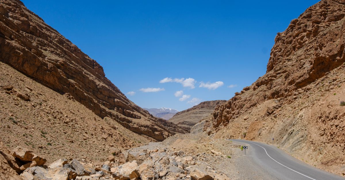 Voiture de location sur une route en lacets du Haut Atlas marocain, sommets et village berbère en arrière-plan