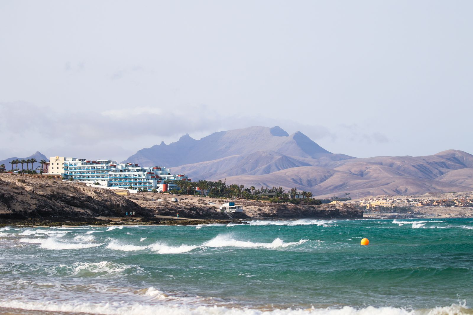 Costa di Fuerteventura con mare mosso, onde bianche e le montagne aride dell'entroterra sullo sfondo