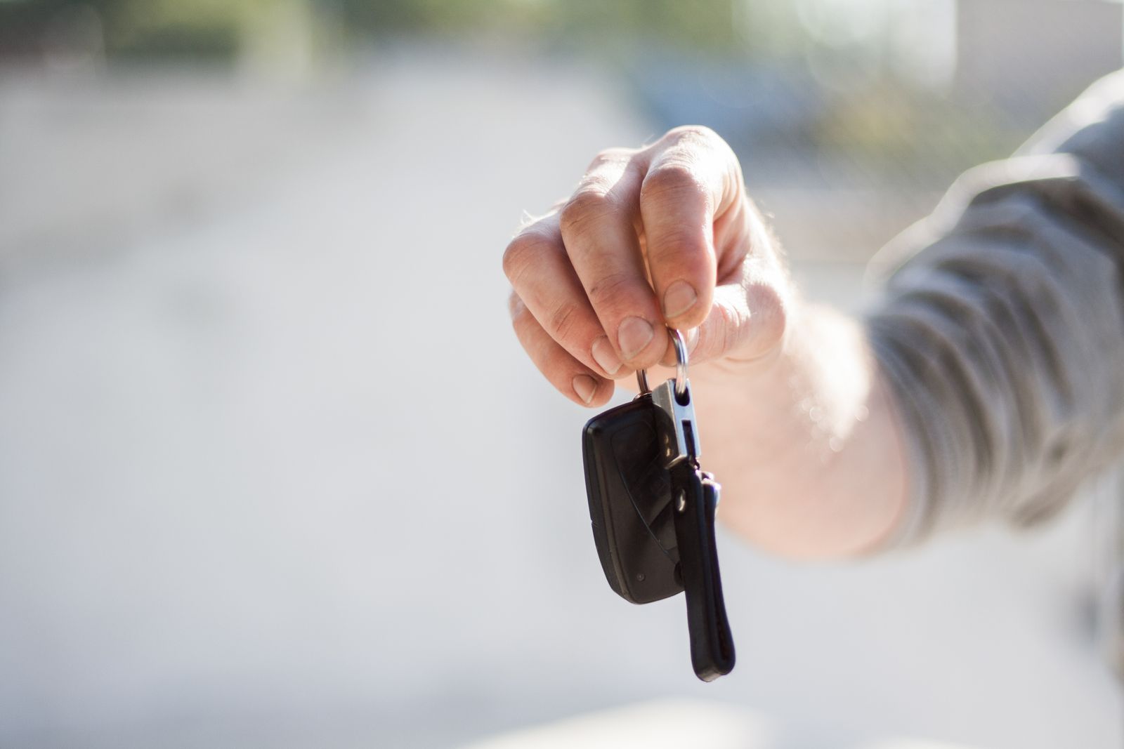 Close-up of a hand handing over a car key at a rental counter