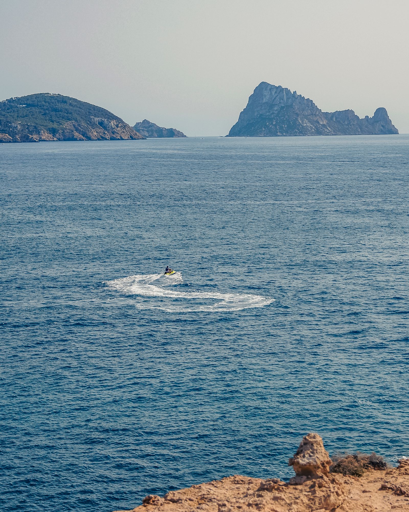 Mietwagen Ibiza: ein Mietwagen auf einer Küstenstraße mit Blick auf die Felseninsel Es Vedrà
