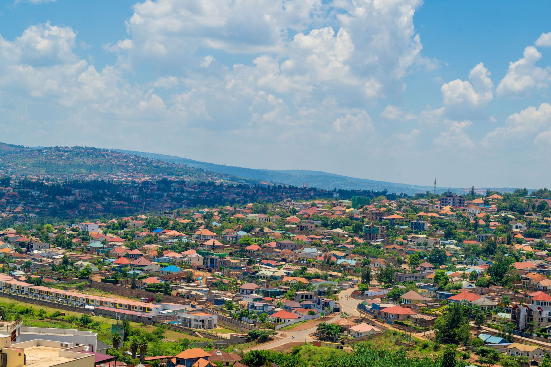Rent a Car in Kigali: Aerial view of Kigali's green hills and red-roofed neighbourhoods under a blue sky, Rwanda