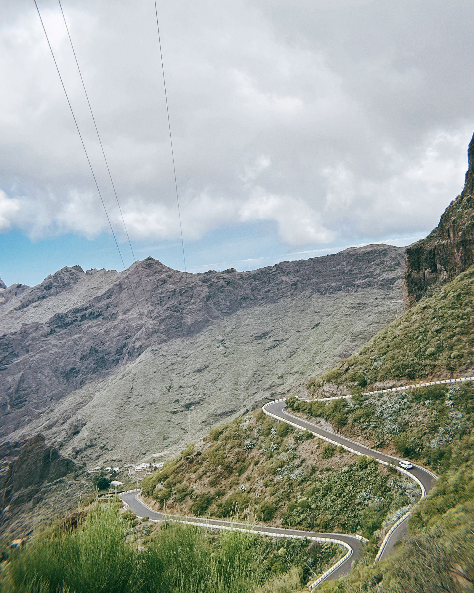 Location de voiture à Tenerife : une voiture de location sur une route côtière avec le Teide en arrière-plan