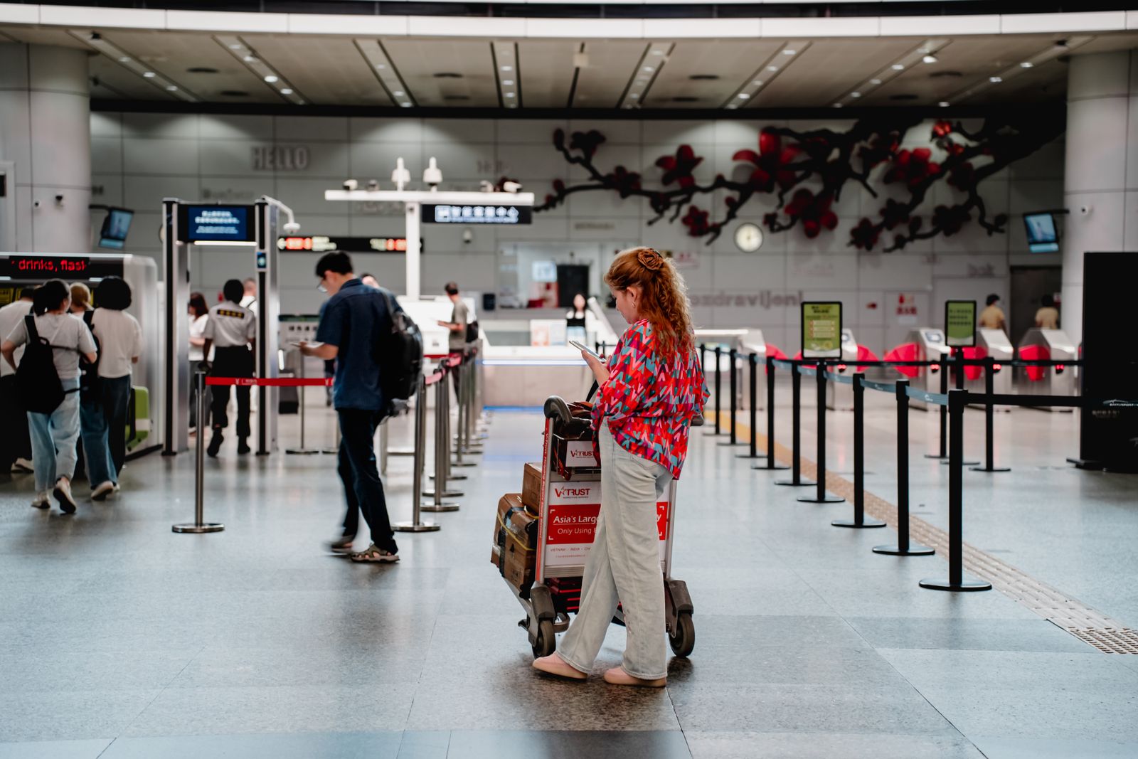 Voyageur consultant son téléphone dans le hall d'un aéroport avec des bagages à côté