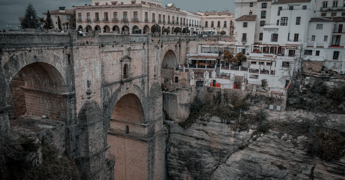 Mietwagen auf einer kurvigen Landstraße bei Ronda mit weißen Dörfern und Bergen Andalusiens im Hintergrund