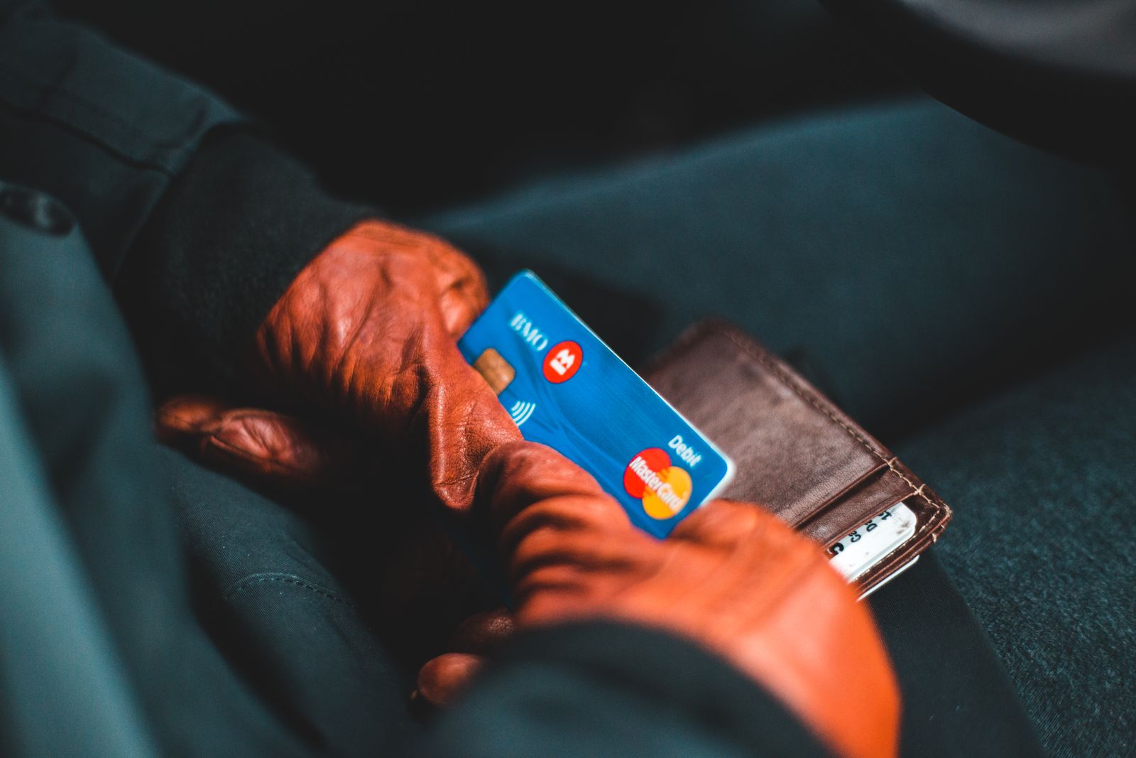 Hand mit einer Bankkarte und einer Geldbörse
