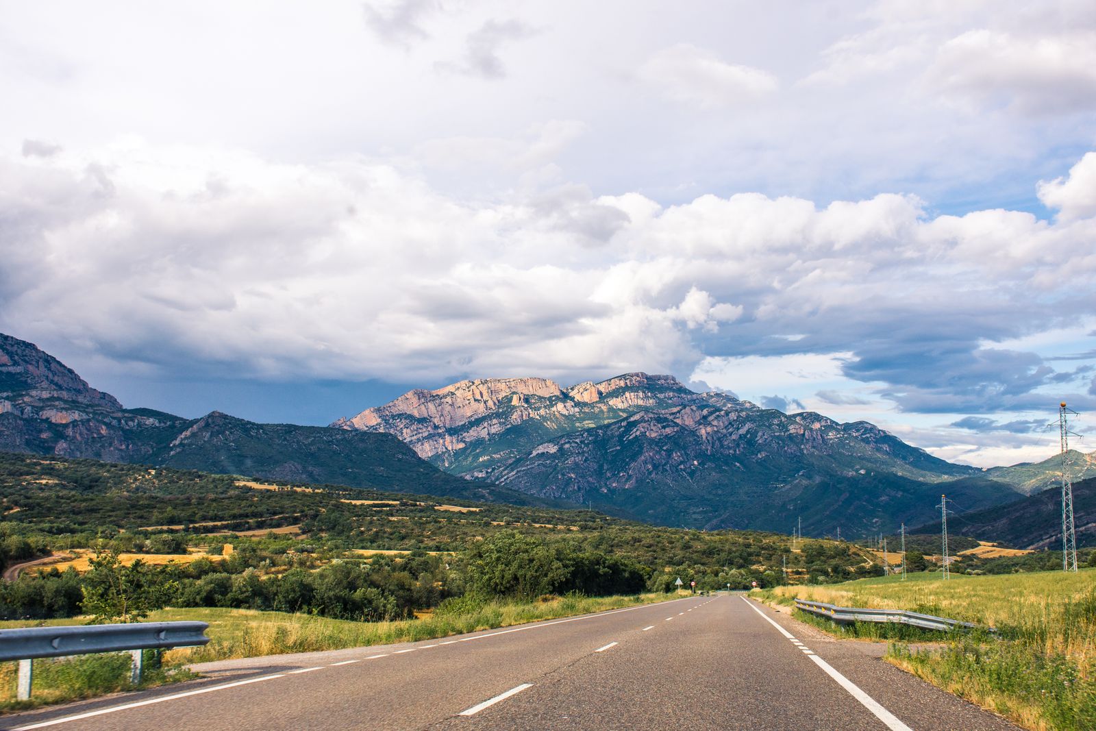 Route traversant un paysage de montagne en Espagne sous un ciel nuageux