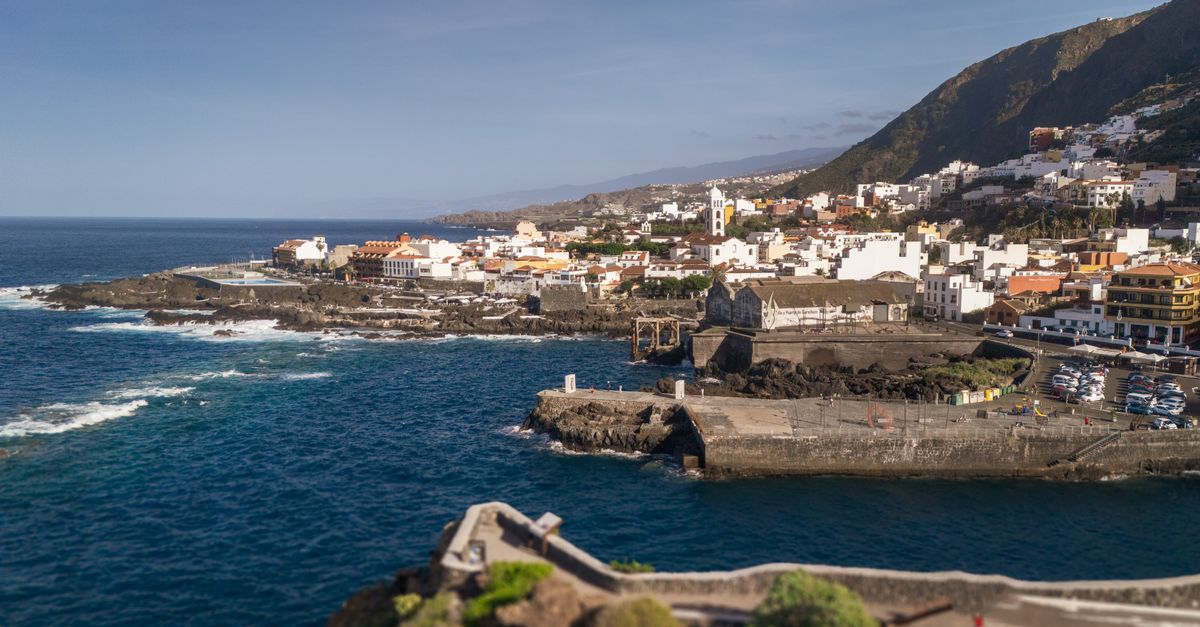 Coche en una carretera de curvas de montaña en Tenerife con el caserío de Masca al fondo y el mar de Canarias