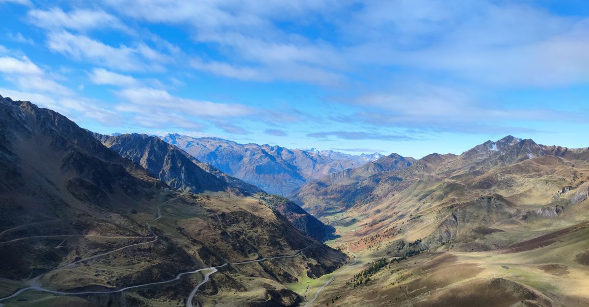 Auto su una strada di montagna nei Pirenei con cime innevate sullo sfondo