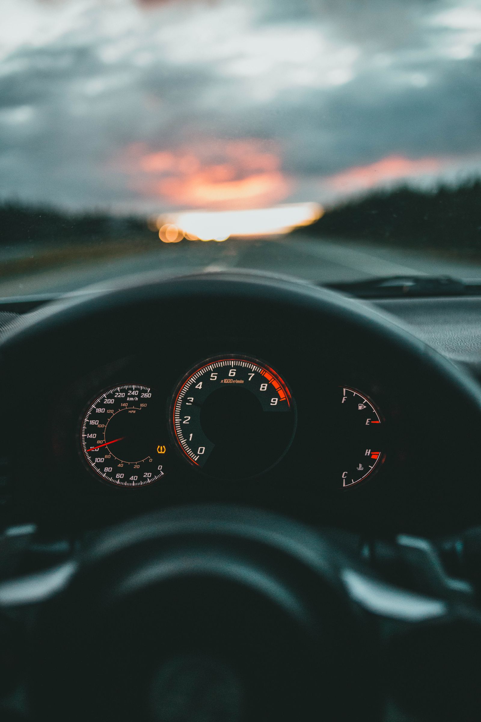 Car dashboard and speedometer on an open road at sunset