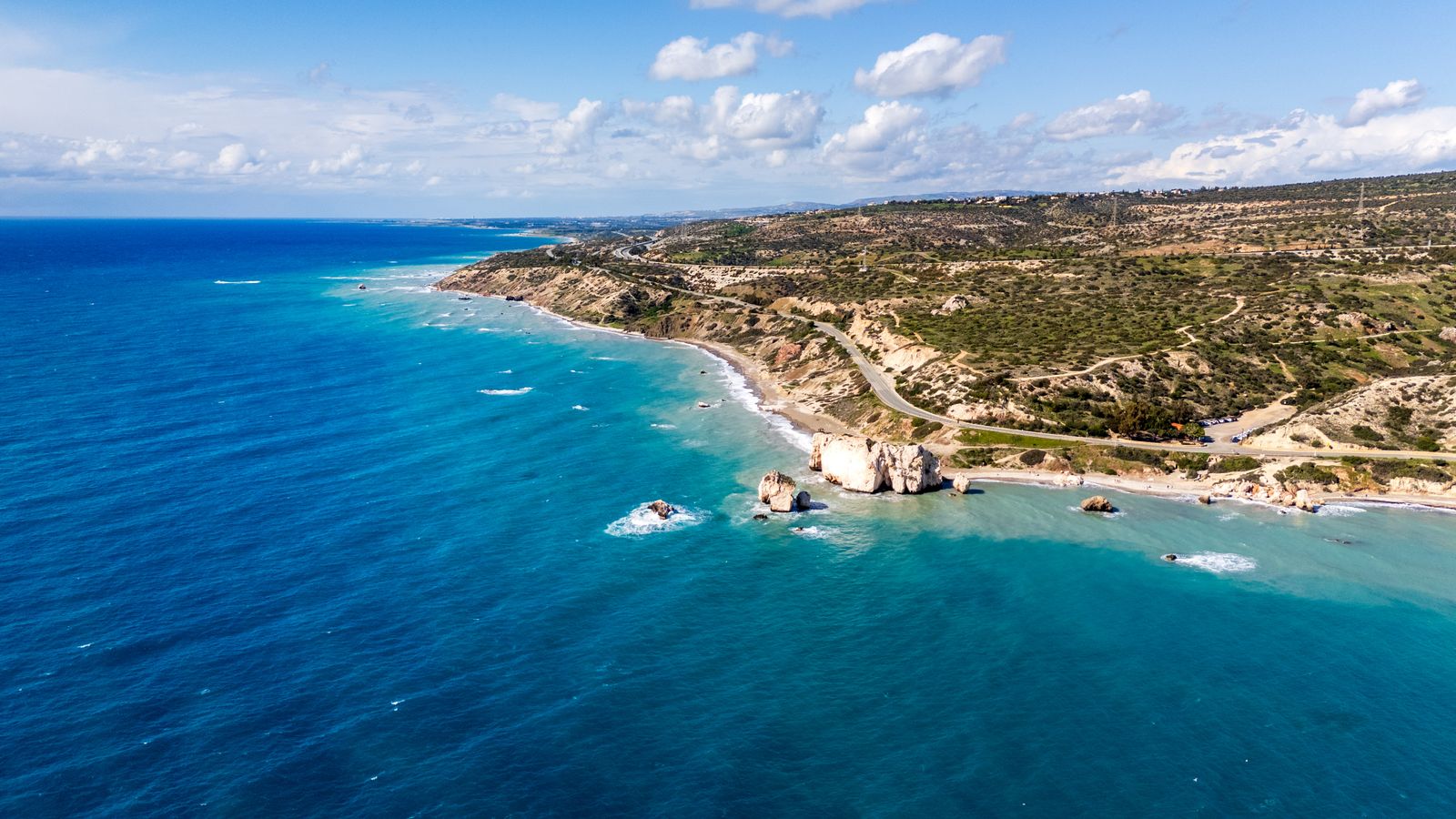 Luftaufnahme der zyprischen Südküste beim Aphrodite-Felsen mit türkisem Meer und der Küstenstraße B6 im Hintergrund